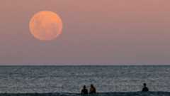 Beachgoers in Australia watch the full moon rise on May 26, 2021.