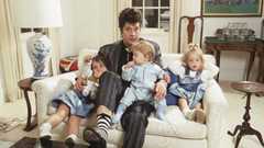 Ozzy Osbourne at home, sitting on the sofa with his three young children