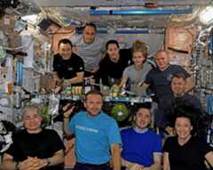 The 10 people living and working on the International Space Station share dinner in a photograph shared by cosmonaut Oleg Novitsky on Oct. 14, 2021.