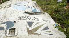 A white metal piece of space debris lies on a grassy lawn with the words "UK Space" upside down with the logo.