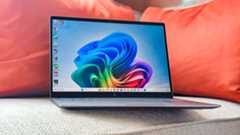 HP OmniBook X 14 resting on a couch with orange cushions behind it.