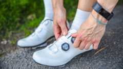 Female cyclist putting on a pair of the best cycling shoes.