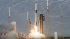 A white rocket blasts off next to a black launch tower.