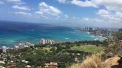 A photo of the Honolulu beaches next to a city and green island landscape