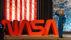 people in blue jumpsuits smile and wave.