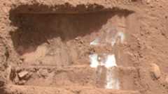 A close up of a the reddish-brown surface of Mars with white streaks across it