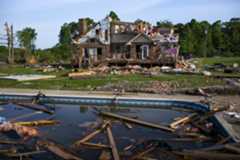 a photo of a destroyed house with debris floating in a pool in the foreground