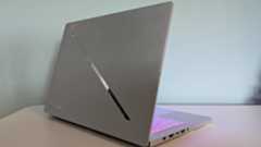 Back three-quarter view of Asus ROG Zephyrus G14 (2025) open on desk with green wall in background