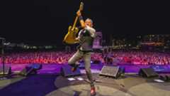Bruce Springsteen onstage holding his guitar aloft and jumping