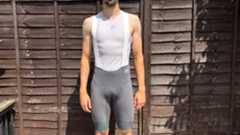 Andy Turner wares the grey MAAP Pro bib shorts 2.0 standing infront of a wooden fence