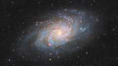 A large spiral galaxy with sweeping spiral arms and a glowing core shines against a sea of stars.