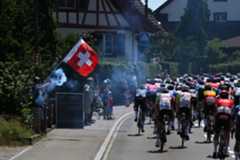 Riders in the Tour de Suisse waved on by a Swiss flag