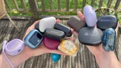 A selection of wireless earbuds, in their cases, held in a woman&#039;s hands on a sunny day