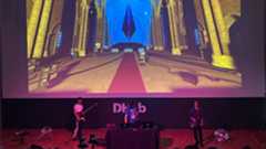 A 3 piece band playing in from of a large digital screen