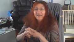 Videogame programmer Rebecca Heineman sitting in home office with clasped hands addressing camera.