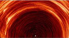 A series of red rings arcing over a white light in the middle of the image