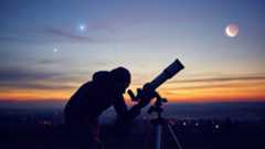 a person looks through a telescope beneath a crescent moon and two bright orbs in the sky