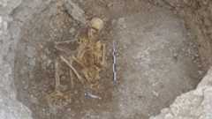 a human skeleton lies face down in a pit