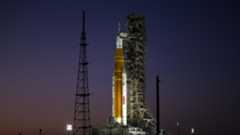 an orange rocket on a launch pad at sunset