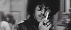 Phil Lynott in sunglasses, smoking a cigarette (1975)