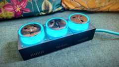 A grey-and-blue Genki Moonbase power strip and charging station sitting on a green sofa