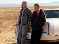 Bryan Cranston (as Walter White) and Aaron Paul (as Jesse Pinkman) rest against the back of a car as they stand in the dessert in Breaking Bad