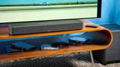 the denon home sound bar 550 with a gray mesh casing and touch controls for bluetooth on the top with a remote and smart home integration