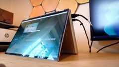 A silver HP Omnibook X Flip 16 2-in-1 laptop on a wooden desk