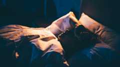 photo of woman lying in bed with an arm resting on her forehead