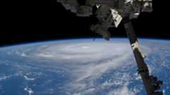a tremendous typhoon is seen on Earth&#039;s horizon from the vantage point of a space station