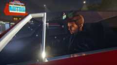 A screenshot from GTA 3 - The Definitive Edition shows a male character sat in a car.