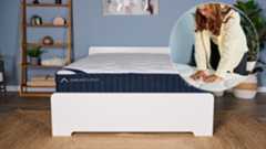The main image shows the DreamCloud Classic Hybrid Mattress on a bed frame in a bedroom. In the left corner is an ident showing mattress tester Eve Davies pressing her hands into the quilted cover of the DreamCloud