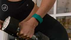 Woman lifting dumbbell while wearing Whoop device on wrist