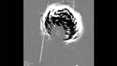 A gray scale image shows a plume of energy coming from the center of the image