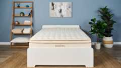 The Saatva Classic luxury innerspring hybrid is the best mattress we've tested, scoring 4.8 out of 5 in our seven robust data-led lab tests and value for money analysis. Here it's photographed on a white wooden bed frame in our blue coloured sleep product testing lab