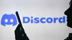 EDMONTON, CANADA - APRIL 28: An image of a woman holding a cell phone in front of the Discord logo displayed on a computer screen, on April 29, 2024, in Edmonton, Canada. 