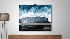 An image of a mounted television displaying an aerial view of waves crashing on a black sand beach, with a secondary lower screen showing the time, date, news headlines about the King&#039;s coronation and Prince Harry, and a KIA logo.