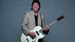 George Thorogood posing for a photograph with a guitar in the early 1980s