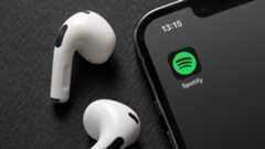 iPhone smartphone screen showing Spotify Music App logo next to two AirPods 
