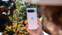 A woman holding up a white Google Pixel 10 Pro XL with colorful plants in the background