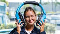 A comically huge set of blue headphones, being held on either side of a model's head