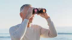 Man holding one of the best budget binoculars in front of the ocean