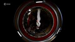 astronaut samantha cristoforetti upside down in a space station module in a white suit