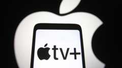 The Apple logo in white glows behind a phone with the Apple TV+ logo on it
