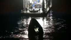 a large barge approaches a white cone-shaped capsule in the ocean