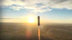 a small rocket carrying six people in a capsule lifts off, set against the rising sun