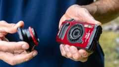 OM System Tough TG-7 in the hand with lens accessory being attached