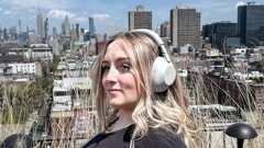 A woman wearing white Sony WH-1000XM6 noise-cancelling headphones