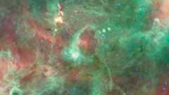 Swirls of green and red gas surrounded a bright white light in the middle of the image