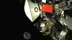 A Chinese flag flies on a metal spacecraft with the Earth in the background in the darkness of space